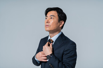 ネクタイを締める60代ビジネスマン