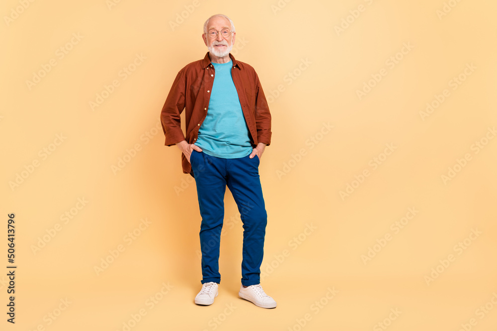 Poster photo of funny sweet guy pensioner dressed brown shirt glasses walking arms pockets isolated beige c