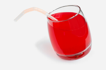 Red juice and a tube in a glass glass on a white background. Selective focus