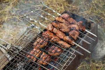 Grill grate with beef meat on a brazier with flaming charcoal