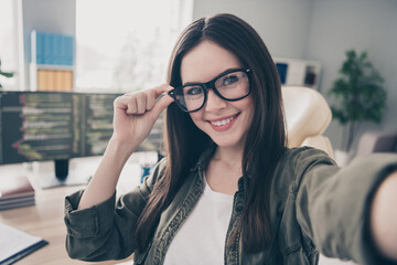 Self-portrait of attractive cheerful skilled girl touching specs tech company leader at workplace workstation indoors