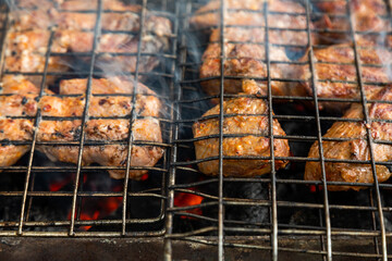Closeup of grill grate with beef meat on a brazier with flaming charcoal