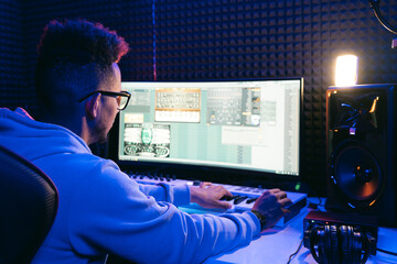 Producer, audio engineer uses a control panel and screen to record a track of a new album in a...