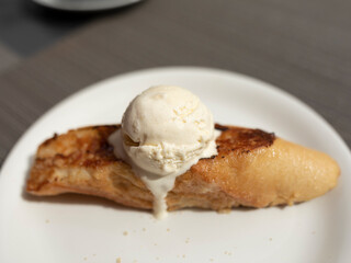A delicious caramelized torrija with honey, and a scoop of vanilla ice cream or cream melting, typical sweet dessert of Easter