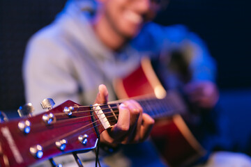Naklejka premium Young afro musician wearing glasses playing acoustic guitar, on dark background