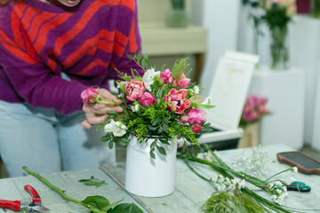 a woman makes a bouquet of fresh flowers in a flower shop
