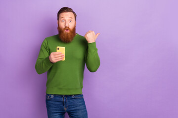 Photo of impressed astonished guy in casual shirt promoting new application program isolated on violet color background - obrazy, fototapety, plakaty