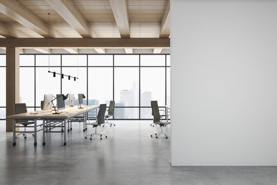 Front view on blank grey wall in light eco style office with stylish workspaces, modern computers, glossy concrete floor, wooden ceiling and city view from big window. 3D rendering, mock up