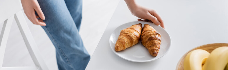 cropped view of woman near plate with delicious croissants, banner