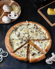 Large pizza with mushrooms and onion on a wooden table with ingredients. Restaurant