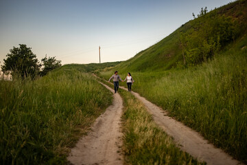 a man and a girl in rustic clothes run along a village road