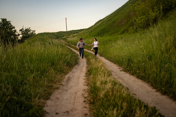 a man and a girl in rustic clothes run along a village road
