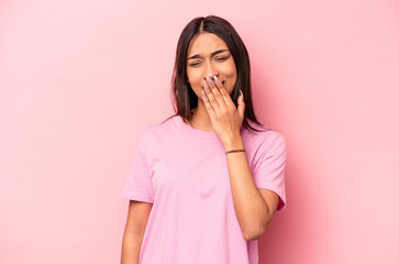 Young hispanic woman isolated on pink background yawning showing a tired gesture covering mouth with hand.