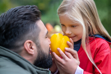 A dark-haired man and his daughter spending time on a farm