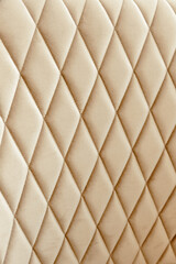 Background of upholstered fabric in beige color with diamond-shaped stitching for furniture, interior items, chairs.