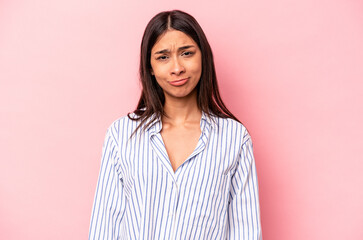 Young hispanic woman isolated on pink background sad, serious face, feeling miserable and displeased.