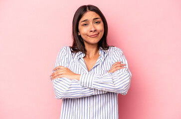 Young hispanic woman isolated on pink background shrugs shoulders and open eyes confused.