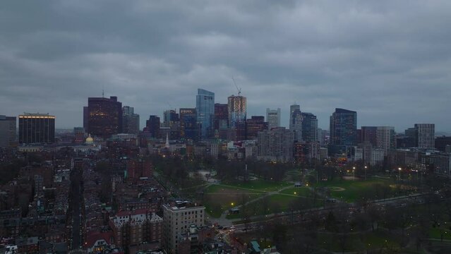 Backwards fly above urban district. Group of modern high rise office buildings against overcast sky at dusk. Boston, USA