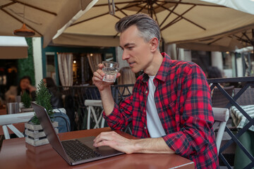Man sitting sideways to camera looking at laptop