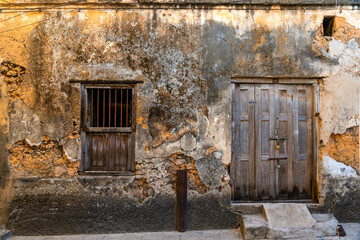 Fototapeta na wymiar old weathered textured building wall with rustic door and window squared up