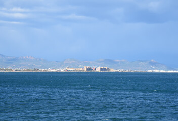 seascape of Mediterranean Sea. Coastline at Alboraya beach. View from sea to cityscape of Port Saplaya against the backdrop of the mountains. View blue seascape ocean. Coastal or coast view.