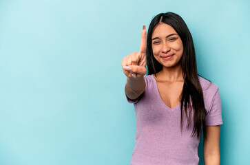 Fototapeta premium Young hispanic woman isolated on blue background showing number one with finger.