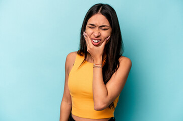 Young hispanic woman isolated on blue background having a strong teeth pain, molar ache.