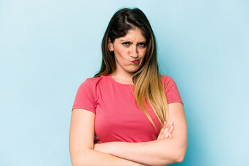 Fototapeta premium Young caucasian woman isolated on blue background frowning face in displeasure, keeps arms folded.