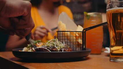 Diverse group of friends out for dinner using knife and fork