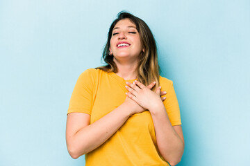 Fototapeta premium Young caucasian woman isolated on blue background has friendly expression, pressing palm to chest. Love concept.