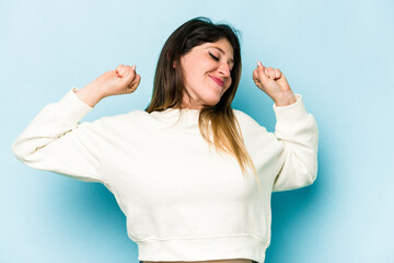 Fototapeta premium Young caucasian woman isolated on blue background stretching arms, relaxed position.