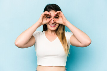 Obraz premium Young caucasian woman isolated on blue background showing okay sign over eyes