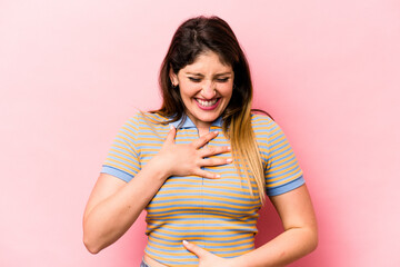 Obraz premium Young caucasian woman isolated on pink background laughs happily and has fun keeping hands on stomach.