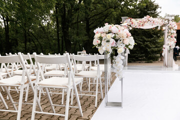 Wedding ceremony decorated with flowers and fabrics in light colors on the arch