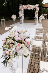 Wedding ceremony decorated with flowers and fabrics in light colors on the arch