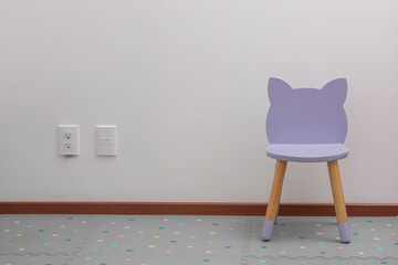 purple children's chair in an office with a white wall and contacts on the wall