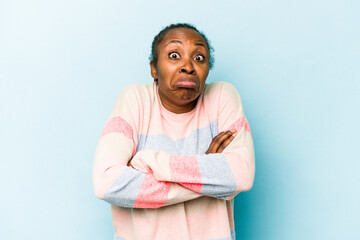 Young african american woman isolated on blue background shrugs shoulders and open eyes confused.