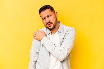 Young hispanic man isolated on yellow background having a shoulder pain.