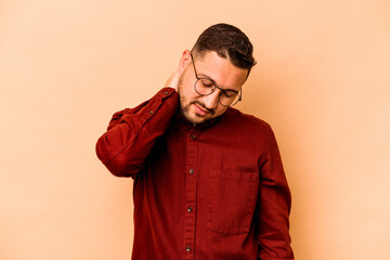 Fototapeta premium Young hispanic man isolated on beige background having a neck pain due to stress, massaging and touching it with hand.