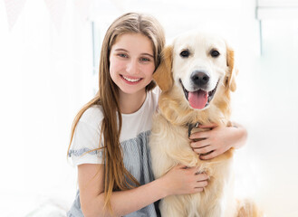Portrait of pretty teenage girl hugging beautiful dog indoors