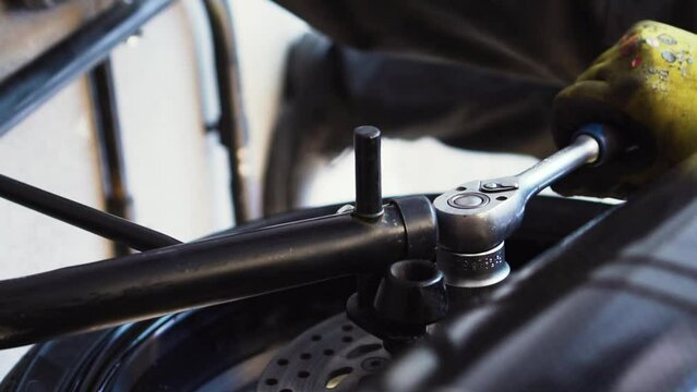 mechanic adjusting the nut of the rear wheel of a motorcycle
