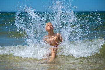 Toddler having fun in water with waves on the beach and splashing
