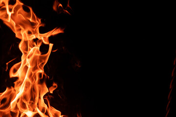 Fototapeta premium Strong orange campfire flame isolated on black night background with copyspace