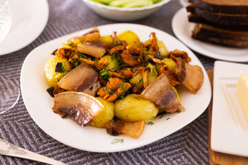 baked potatoes with chanterelles and bacon served with herbs on white plate