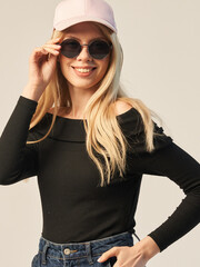 a young fashionable girl in dark glasses a cap a dark top on a white background