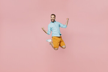 Full body young excited overjoyed caucasian happy man 20s wear classic blue shirt jump high do winner gesture isolated on plain pastel light pink background studio portrait. People lifestyle concept.