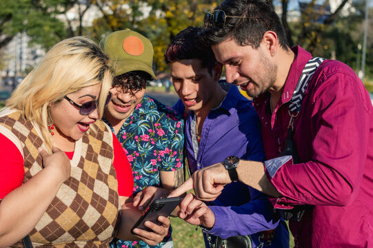 diverse group of friends outdoors together, smiling, checking and pointing at the phone screen