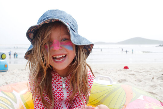Happy girl at the beach wearing hat and sunblock