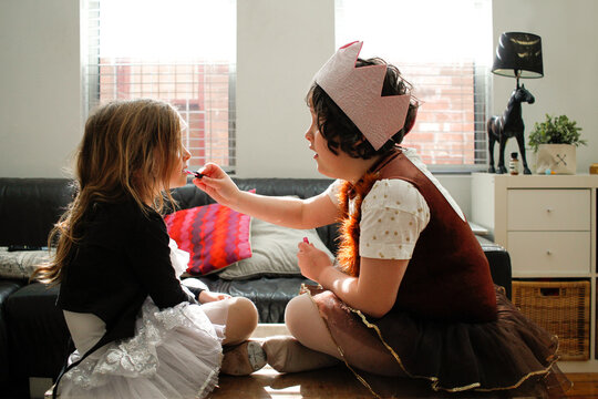 Two girls dressed as princesses playing putting on makeup