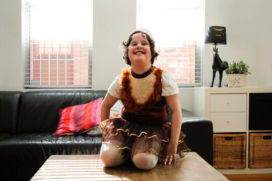 Happy girl on the table wearing a dressups play dress